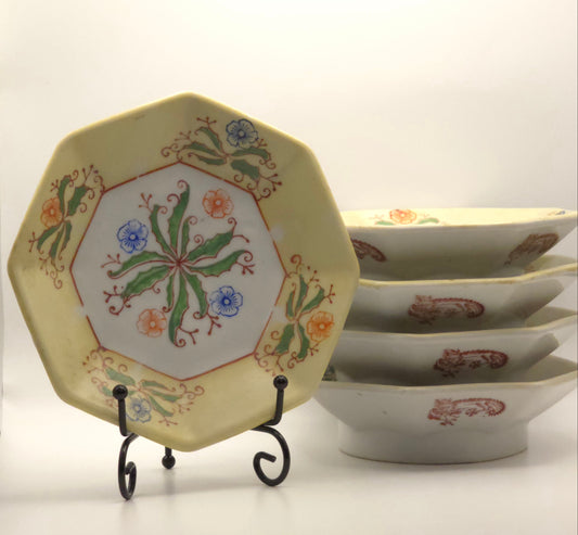 Decorative ceramic plate with floral design on a stand, next to a stack of bowls with red patterns.